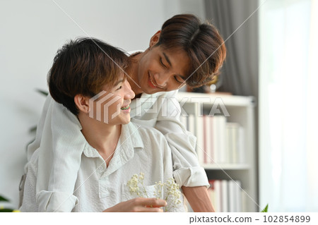 Affectionate romantic male gay couple spending time together, enjoying arranging flowers in cozy home. LGBT, homosexual and love 102854899