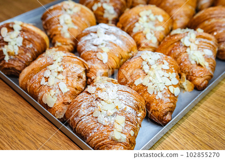 Sprinkle the finished croissants on a baking sheet with almond flakes 102855270