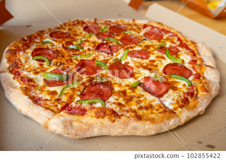 Pepperoni Pizza in Cardboard Delivery Box Closeup, Salami Pizza with Green Paprika, Chili Pepper 102855422