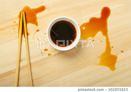 Spilled Soy Sause on Wooden Table, Teriyaki Drops, Oyster Sauce in White Bowl, Balsamic Vinegar Puddles Spilled Soy Sause on Wooden Table, Teriyaki Drops, Oyster Sauce in White Bowl, Balsamic Vinegar Puddles 102855823