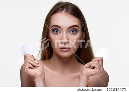 woman holding two white cotton disks pad with micellar water 102856075