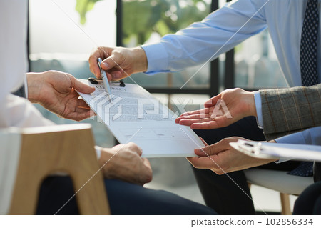 Businessman passing document to manager at the office 102856334