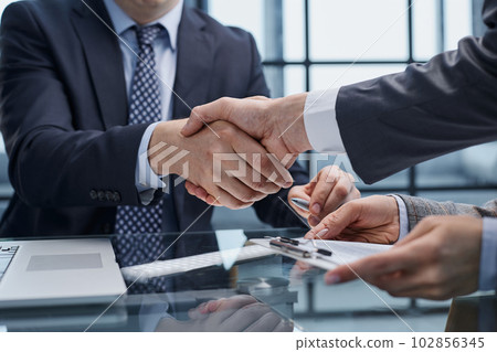Businesspeople or lawyers shaking hands finishing up meeting or negotiation in sunny office. Businesspeople or lawyers shaking hands finishing up meeting or negotiation in sunny office. 102856345