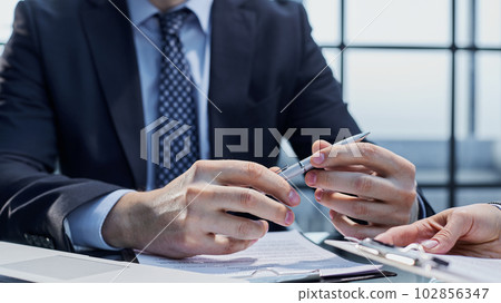 Signing documents. The man is holding a pen and has a contract of employment in front of him. Signing documents. The man is holding a pen and has a contract of employment in front of him. 102856347