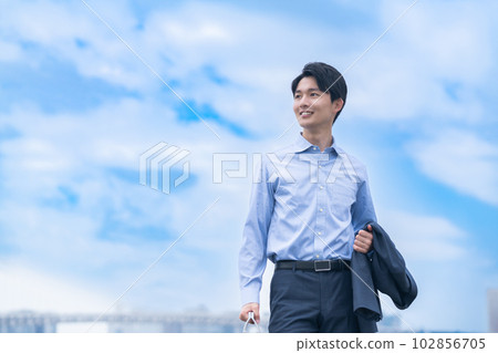 一位年輕的商人穿著脫衣夾克清爽地行走 一位年輕的商人穿著脫衣夾克清爽地行走 102856705