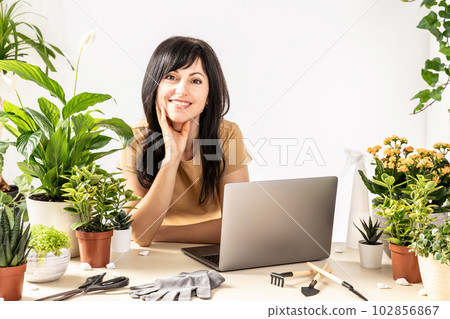 Smiling female using laptop computer at workshop transplantation houseplants Smiling female using laptop computer at workshop transplantation houseplants 102856867