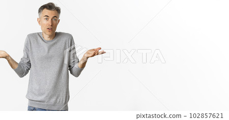 Image of confused middle-aged man shrugging shoulders, looking clueless at camera, standing over white background 102857621
