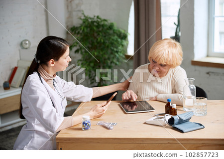 Senior woman and female doctor using gadgets to check patient's health information. In office. Modern medical attitude 102857723