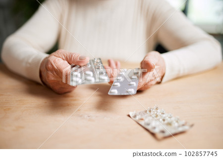 Close-up image of female hands holding pills. Senior woman following her treatment, taking care after health with medical support Close-up image of female hands holding pills. Senior woman following her treatment, taking care after health with medical support 102857745