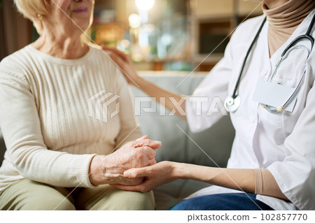 Cropped image of female doctor giving support and hope to her elderly patient. Woman holding hand of senior lady 102857770