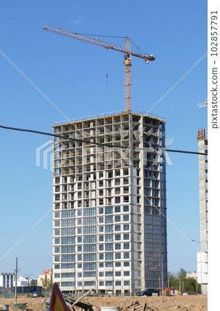Construction site. Reinforced concrete frame of a multi-storey building and construction cranes. The final stage of construction. Against the background of the blue sky. 102857791