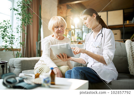 Senior woman at doctor appointment, consultation checking health in clinic, hospital on daytime. Doctor showing information on tablet 102857792