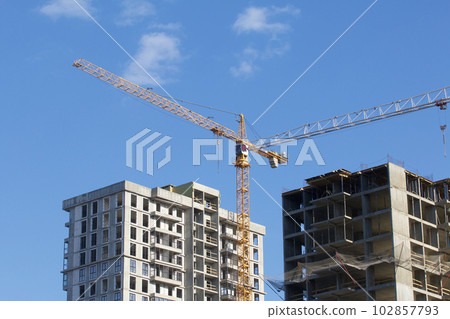 Construction site. Reinforced concrete frames of multi-storey buildings and construction cranes. Against the background of the blue sky. 102857793