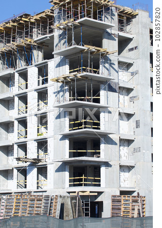 Construction site. Reinforced concrete frames of multi-storey buildings and construction cranes. Against the background of the blue sky. Construction site. Reinforced concrete frames of multi-storey buildings and construction cranes. Against the background of the blue sky. 102857820