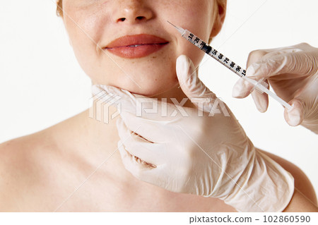 Anti-wrinkles care. Cropped image of female face with syringe making beauty filler injection against white studio background 102860590