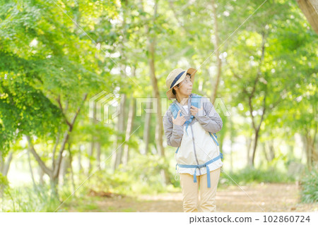 Photo of a senior woman hiking in fresh green 102860724