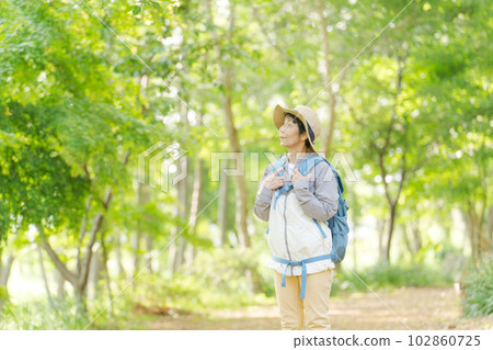 Photo of a senior woman hiking in fresh green 102860725