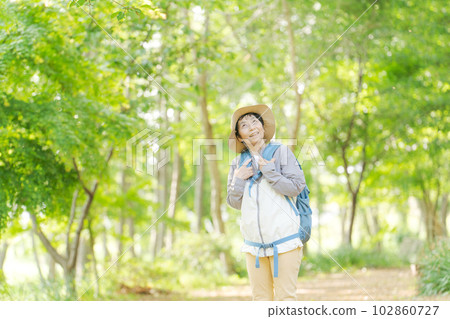 Photo of a senior woman hiking in fresh green 102860727