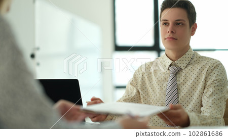 Businessman giving document for signature to partner in office Businessman giving document for signature to partner in office 102861686