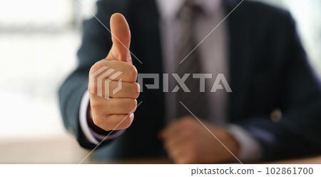 Businessman in suit showing thumbs up on successful deal closeup Businessman in suit showing thumbs up on successful deal closeup 102861700