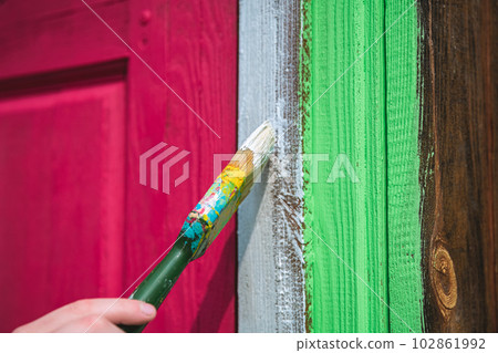 girl painting the door of a wooden house in a bright purple viva magenta color girl painting the door of a wooden house in a bright purple viva magenta color 102861992