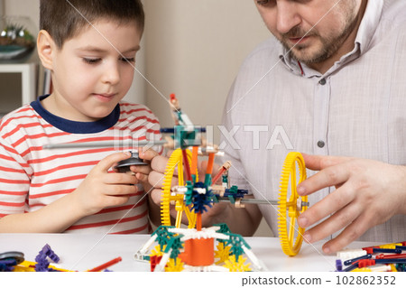 Dad and son build figures from the constructor. Spending time together, the role of the father in the child's life Dad and son build figures from the constructor. Spending time together, the role of the father in the child's life 102862352