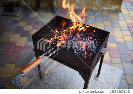 Empty flaming charcoal grill with open fire, ready for product placement. Concept of summer grilling, barbecue, bbq and party. Empty flaming charcoal grill with open fire, ready for product placement. Concept of summer grilling, barbecue, bbq and party. 102862508