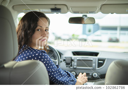 Young stylish woman driver sitting behind steering wheel of her car. Driving vehicle concept 102862786