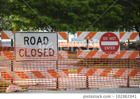 Yellow protective fence barrier at street construction site. Warning road sign about utility work Yellow protective fence barrier at street construction site. Warning road sign about utility work 102862841