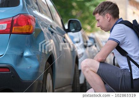 Stressed man driver sitting on street side shocked after car accident. Road safety and insurance concept 102863319
