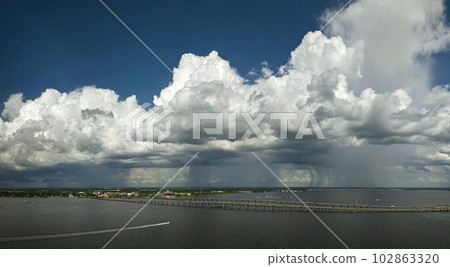 Stormy clouds forming from evaporating humidity of ocean water before thunderstorm over traffic bridge connecting Punta Gorda and Port Charlotte over Peace River. Bad weather conditions for driving Stormy clouds forming from evaporating humidity of ocean water before thunderstorm over traffic bridge connecting Punta Gorda and Port Charlotte over Peace River. Bad weather conditions for driving 102863320