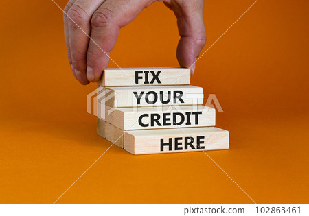 Fix your credit here symbol. Concept words Fix your credit here on wooden blocks on a beautiful orange table orange background. Businessman hand. Business, finacial and fix your credit here concept. 102863461