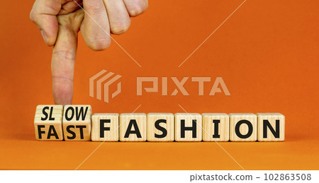 Fast or slow fashion symbol. Concept words Fast fashion and Slow fashion on wooden cubes. Businessman hand. Beautiful orange table orange background. Business fast or slow fashion concept. Copy space. Fast or slow fashion symbol. Concept words Fast fashion and Slow fashion on wooden cubes. Businessman hand. Beautiful orange table orange background. Business fast or slow fashion concept. Copy space. 102863508