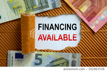 The text 'financing available' appearing behind torn brown paper. Euro bills. Business concept. The text 'financing available' appearing behind torn brown paper. Euro bills. Business concept. 102863536