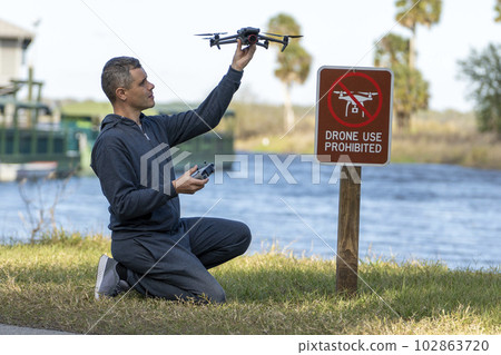 Man is going to fly his quadcopter in no drone area. Operator unlawfully using his UAS in state park near restriction sign 102863720