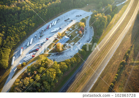 Large truck stop with resting area near busy american interstate freeway with fast driving cars and trucks. Recreational parking place during interstate travel 102863728