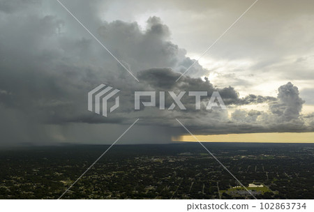 Landscape of dark ominous clouds forming on stormy sky during heavy thunderstorm over rural town area 102863734