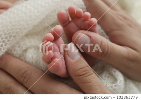 Mother is doing massage on her baby foot. Closeup baby feet in mother hands. Prevention of flat feet, development, muscle tone, dysplasia. Family, love, care, and health concepts. Studio macro. Mother is doing massage on her baby foot. Closeup baby feet in mother hands. Prevention of flat feet, development, muscle tone, dysplasia. Family, love, care, and health concepts. Studio macro. 102863779