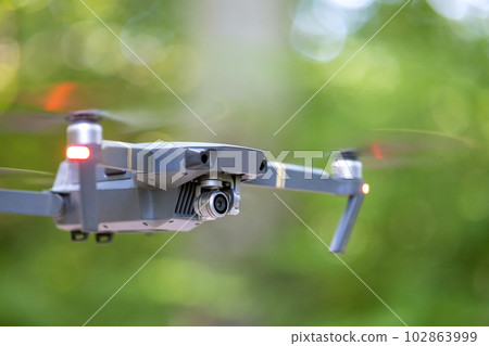 Drone aircraft with blurred fast rotating propellers and video camera flying in air. Drone aircraft with blurred fast rotating propellers and video camera flying in air. 102863999