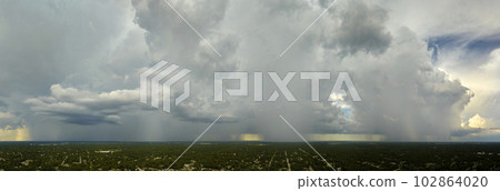 Dark stormy clouds forming on gloomy sky during heavy rainfall season over suburban town area 102864020