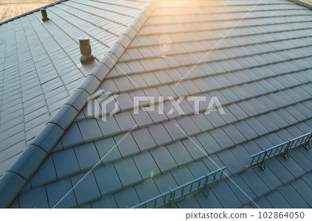 Closeup of house roof top covered with ceramic shingles. Tiled covering of building Closeup of house roof top covered with ceramic shingles. Tiled covering of building 102864050