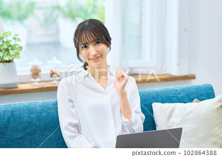 Young woman operating a personal computer in the living room Young woman operating a personal computer in the living room 102864388