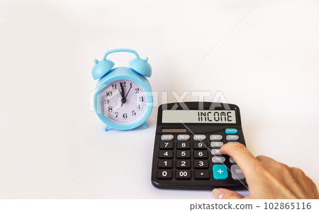 A woman's hand presses on a calculator, on the display of which the word INCOME. A woman's hand presses on a calculator, on the display of which the word INCOME. 102865116