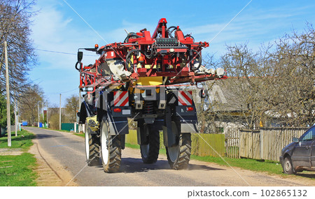 Agricultural machinery rides along a rural road on a field 102865132
