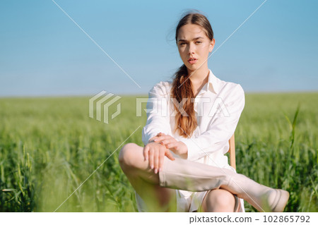 Young woman in white suit posing in green wheat field. Fashion and lifestyle concept. 102865792