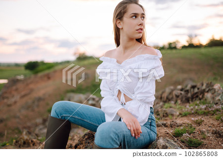 Young cheerful woman wearing cowgirl boots posing in the countryside. Fashion, style, lifestyle concept 102865808