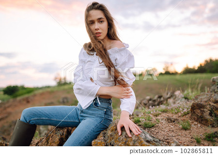 Young cheerful woman wearing cowgirl boots posing in the countryside. Fashion, style, lifestyle concept 102865811
