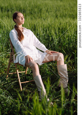 Young woman in white suit posing in green wheat field. Fashion and lifestyle concept. 102865813