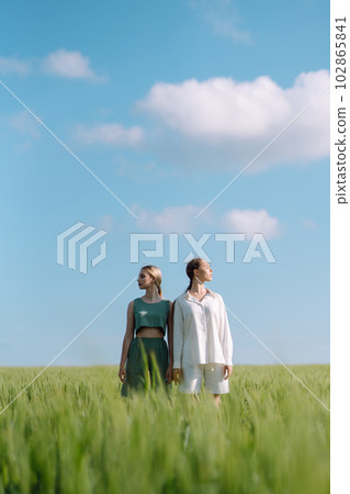 Two Beautiful woman in the green field. Nature, vacation, relax and lifestyle. Summer landscape. Two Beautiful woman in the green field. Nature, vacation, relax and lifestyle. Summer landscape. 102865841
