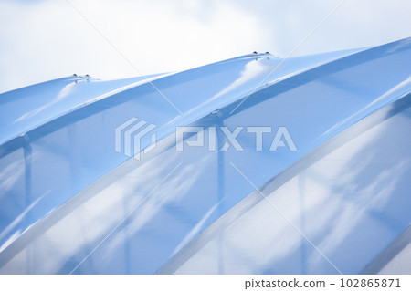 Transparent flexible roof of a greenhouse is under bright blue sky 102865871